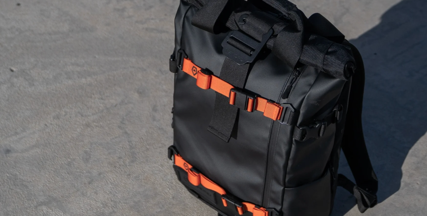 Black backpack with orange straps on a gray surface
